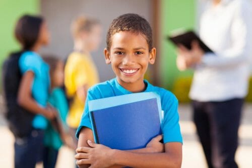 Young male student holding school work and smiling